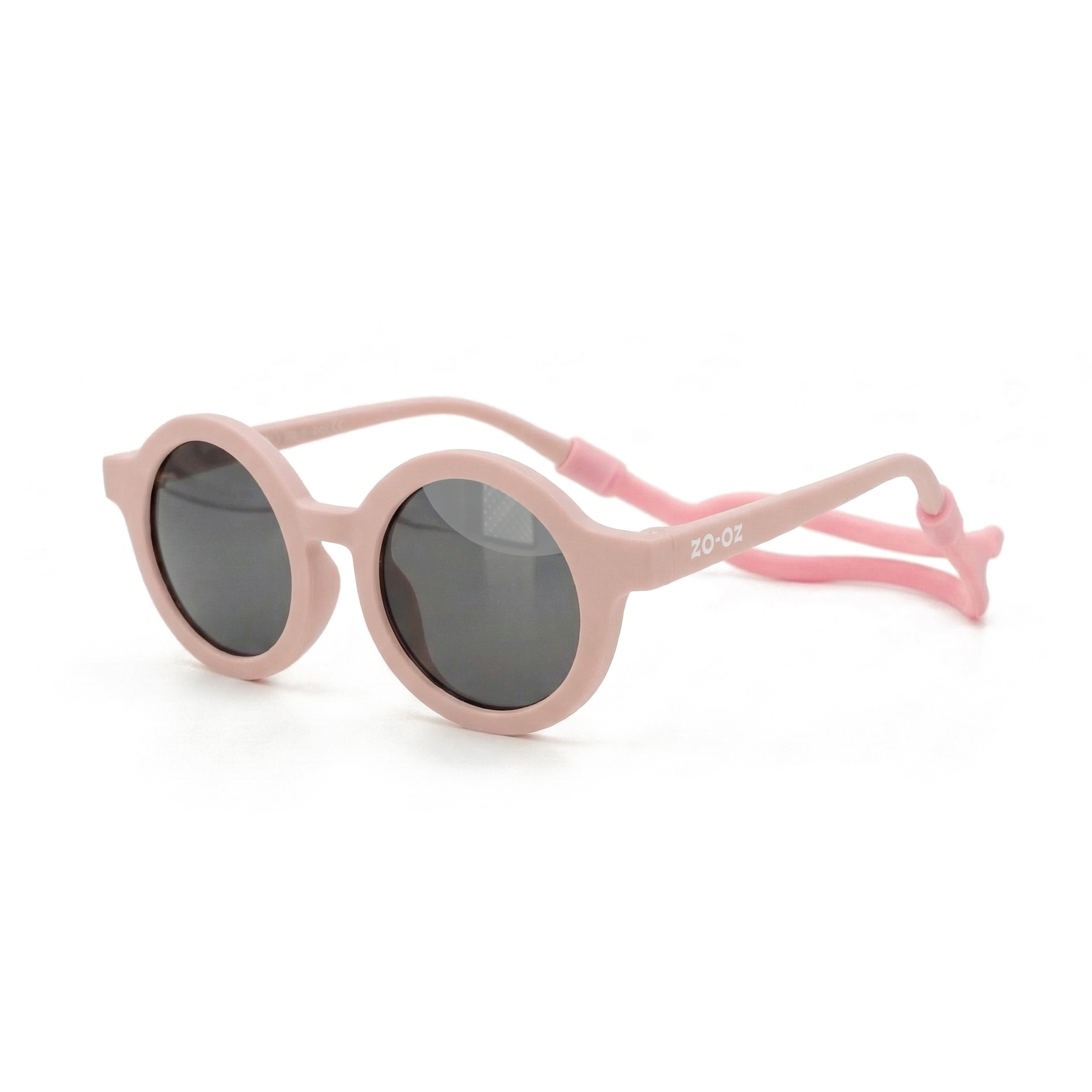 Occhiali da sole zo-oz stile tondo modello Bam rosa opaco con fascetta rosa per bambini 0-2 anni. Inquadratura laterale in prospettiva con le aste aperte appoggiate su una superficie.