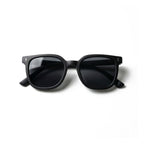 Occhiali da sole zo-oz stile wayfarer modello Zip nero opaco per bambini 6-12 anni piegati e fotografati dall'alto.